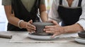 Young woman potter and mature woman making ceramic pot from clay in pottery workshop. Activity, handicraft, hobbies