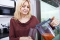 Young woman pouring carrot juice in glass at kitchen Royalty Free Stock Photo