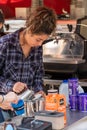 Young woman pouring a coffee or hot chocolate from a jug at counter on a coffee cart