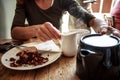 Young woman pouring cup of tea and eating cake in cafe Royalty Free Stock Photo