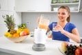 Young woman pouring juice from blender in the glass Royalty Free Stock Photo