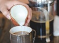 Young woman pouring milk into cup of filtered coffee Royalty Free Stock Photo