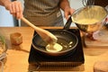 Young woman pouring pancake batter onto a hot electric griddle, couple preparing breakfast together