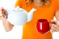 Young Woman Pouring Tea from a Teapot Holding Teapot and Mug Royalty Free Stock Photo