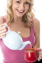 Young Woman Pouring Tea from a Teapot into Mug Royalty Free Stock Photo