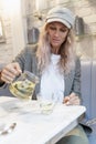 A young woman pours herself tea in a cafe. Modern pretty blonde in a cap. Health care. Vertical Royalty Free Stock Photo