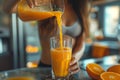 A young woman pours orange juice into a glass