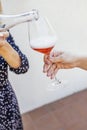 A young woman pours pink champagne from a transparent bottle