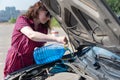 Young woman pours windshield washer fluid into the tank Royalty Free Stock Photo