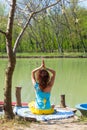 Young woman practice yoga outdoor by the lake healthy lifestyle concept back view full body shot Royalty Free Stock Photo