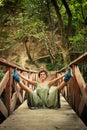 young woman practice yoga outdoor on the small wooden river bridge