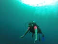 Young woman practices the sport scuba diving with oxygen tank equipment, visor, fins, relaxes and enjoys the bottom of the crystal Royalty Free Stock Photo