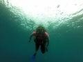 Young woman practices the sport scuba diving with oxygen tank equipment, visor, fins, relaxes and enjoys the bottom of the crystal Royalty Free Stock Photo