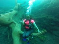 Young woman practices the sport scuba diving with oxygen tank equipment, visor, fins, relaxes and enjoys the bottom of the crystal Royalty Free Stock Photo