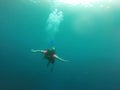 Young woman practices the sport scuba diving with oxygen tank equipment, visor, fins, relaxes and enjoys the bottom of the crystal Royalty Free Stock Photo