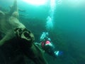 Young woman practices the sport scuba diving with oxygen tank equipment, visor, fins, relaxes and enjoys the bottom of the crystal Royalty Free Stock Photo