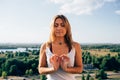 Young woman practices yoga outside. Calm smiling blonde girl with close eyes. Her fingers fold into sign of infinity Royalty Free Stock Photo