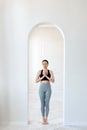 A young woman practices yoga, prays and comprehends Zen in the arch of a bright room. The concept of a healthy lifestyle