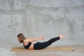 Young woman practicing advanced yoga in sports black jersey in the studio. Superman Pose.