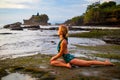 Young woman practicing Ardha Kapotasana, Half Pigeon Pose. Chest opener improving breathing. Water reflection. Tanah Lot beach, Royalty Free Stock Photo