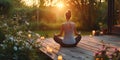 Young woman practicing breathing yoga pranayama outdoors on wooden terrace surrounded with candles, on early morning. Unity with