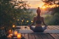 Young woman practicing breathing yoga pranayama outdoors on wooden terrace surrounded with candles, on early morning. Unity with