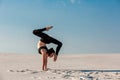 Young woman practicing handstand on beach with white sand and bright blue sky Royalty Free Stock Photo