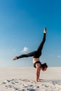 Young woman practicing handstand on beach with white sand and bright blue sky Royalty Free Stock Photo