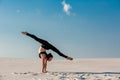 Young woman practicing handstand on beach with white sand and bright blue sky Royalty Free Stock Photo