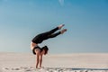 Young woman practicing handstand on beach with white sand and bright blue sky Royalty Free Stock Photo