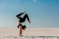 Young woman practicing handstand on beach with white sand and bright blue sky Royalty Free Stock Photo