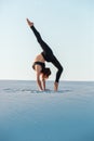 Young woman practicing inversion balancing yoga pose handstand on sand. Royalty Free Stock Photo