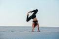 Young woman practicing inversion balancing yoga pose handstand on sand. Royalty Free Stock Photo