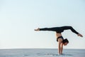 Young woman practicing inversion balancing yoga pose handstand on sand. Royalty Free Stock Photo