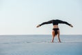 Young woman practicing inversion balancing yoga pose handstand on sand. Royalty Free Stock Photo