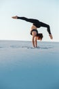 Young woman practicing inversion balancing yoga pose handstand on sand. Royalty Free Stock Photo