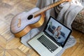 Young woman practicing and learning how to play guitar on laptop computer monitor. Female guitarist watching online