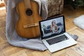 Young woman practicing and learning how to play guitar on laptop computer monitor. Female guitarist watching online