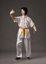 Young woman practicing tai chi chuan. Chinese management skill Qi`s energy. Gray background, studio shoot. Royalty Free Stock Photo