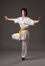Young woman practicing tai chi chuan. Chinese management skill Qi`s energy. Gray background, studio shoot. Royalty Free Stock Photo