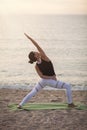 Young woman practicing yoga on the beach. Reverse Warrior Pose, Viparita Virabhadrasana. Outdoors sports. Healthy living. Royalty Free Stock Photo