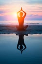 Young woman practicing yoga on the beach at sunset Royalty Free Stock Photo