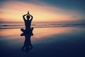 Young woman practicing yoga on beach at surrealistic sunset.