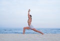 Young woman practicing yoga on the beach. Virabhadrasana I pose Royalty Free Stock Photo