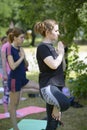 Young woman practicing yoga at the city park, group of people meditating on a background