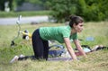 Young woman practicing yoga at the city park, group of people meditating on a background