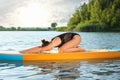 Young woman practicing yoga on color SUP board on river Royalty Free Stock Photo