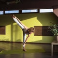 Young woman practicing yoga doing Adhomukha Utthitahasta padangushthasana exercise, leg stretch pose