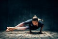 Young woman practicing yoga doing eight-angle pose asana in dark room Royalty Free Stock Photo