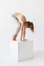A young woman practicing yoga, doing a preparatory exit for the exercise eka pada bhujapidasana, preparing for a handstand Royalty Free Stock Photo